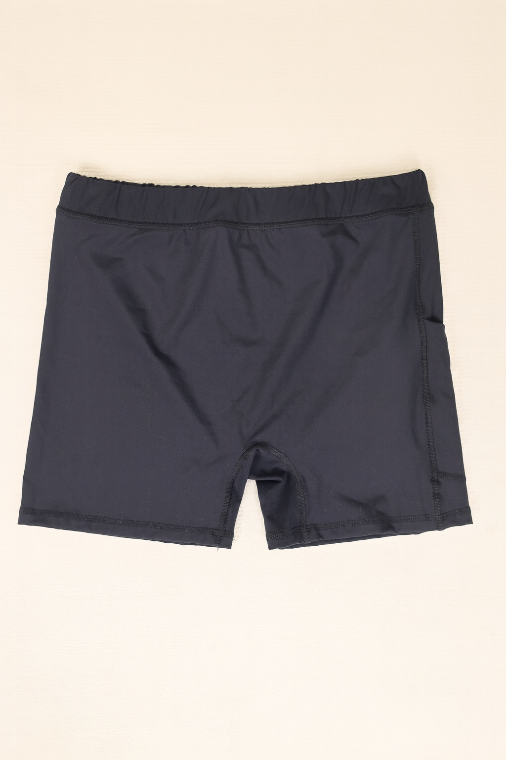 Folded black shorts on a beige background